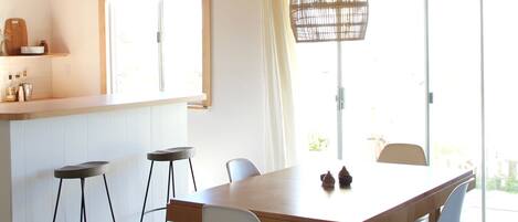 A modern kitchen with wooden beams, a large island, bar stools, and pendant lighting.