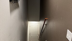 A narrow hallway with a wooden floor, a white door at the end, and a black wall-mounted rack on the left. - Edwards condo with attached garage (Edwards)