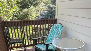 A patio with two chairs and a table, surrounded by a wooden fence and a house. - Edwards condo with attached garage (Edwards)