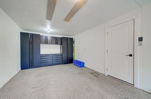Une pièce avec une porte blanche, un meuble de rangement bleu et un tapis gris.