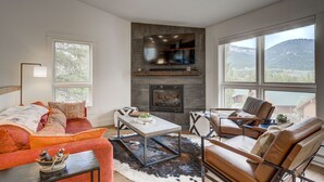 Un salon moderne avec une cheminée, un canapé, une table basse et une vue sur l’extérieur.