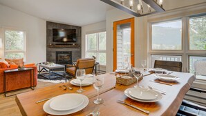 Un coin repas avec une table en bois dressée pour quatre personnes, une cheminée et un téléviseur placé au-dessus.