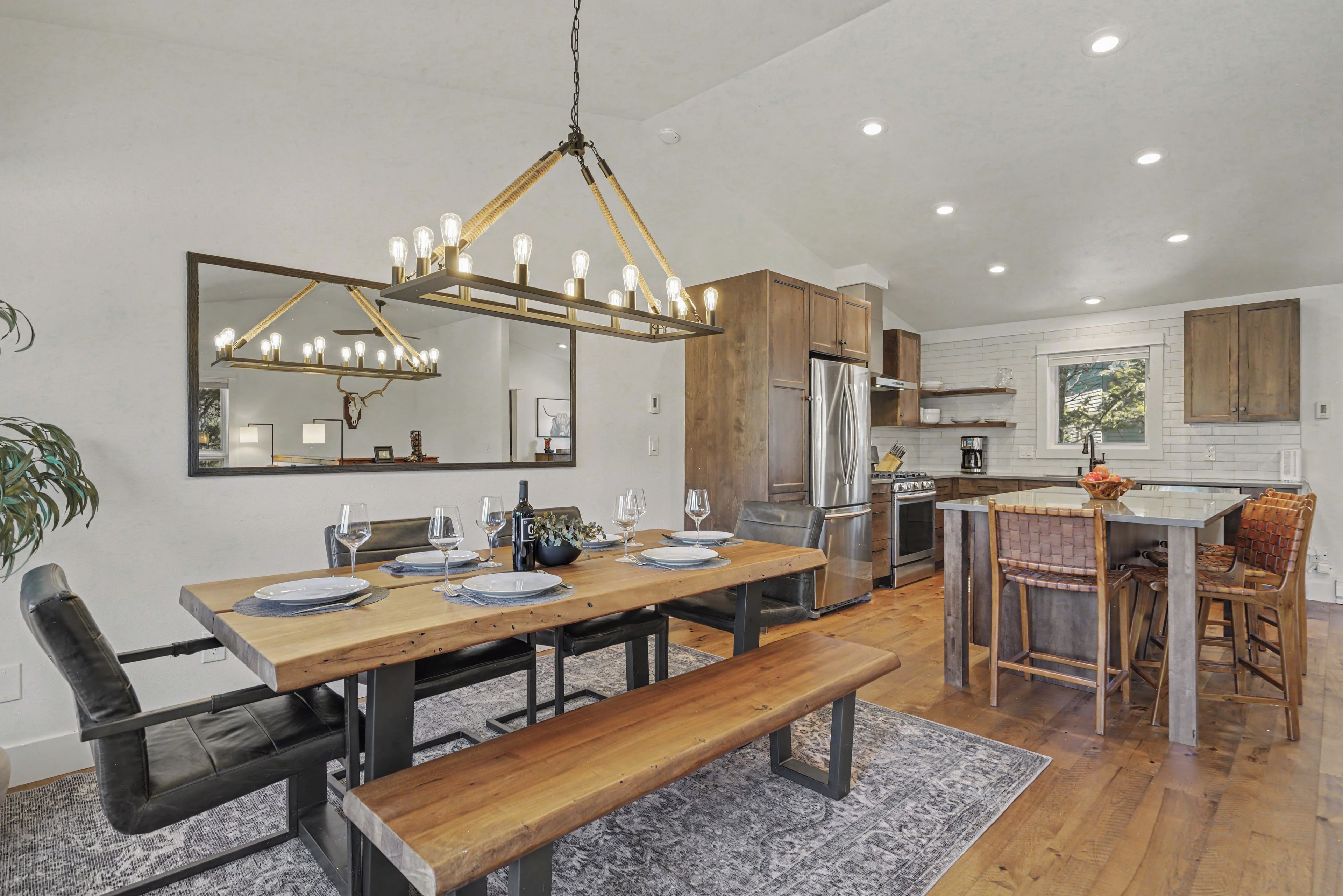 A modern kitchen with a central island, stainless steel appliances, and a dining area with a wooden table and benches.