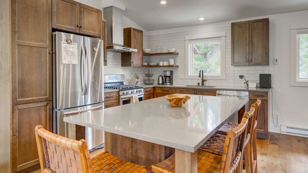 Une cuisine moderne avec des meubles en bois, des appareils électroménagers en acier inoxydable et un îlot central.
