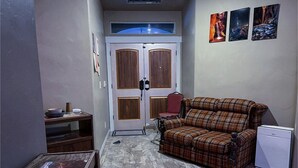 A small, compact room with a plaid sofa, a small table, and a radiator.