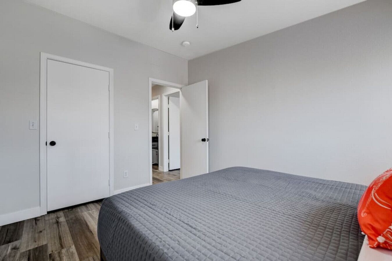 Un dormitorio con cama, dos puertas blancas y un pasillo que conduce a otra habitación.