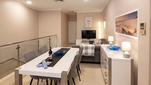 Un soggiorno moderno con zona pranzo, divano, televisore e camino.