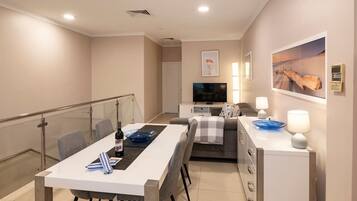 A modern living room with a dining area, a sofa, a TV, and a fireplace.