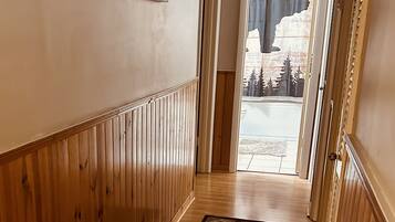 A hallway with wooden paneling, a patterned rug, and a view of a mountain landscape through a door.