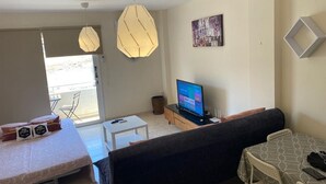 Uma sala de estar com sofá, televisão e um espaço de jantar com mesa e cadeiras.