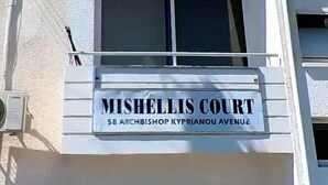 Um edifício com uma placa que diz 'MISHELLIS COURT 58 ARCHBISHOP KYPRIANOU AVENUE'.