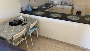 Uma cozinha compacta com área de refeições, com fogão, pia e máquina de lavar roupa.