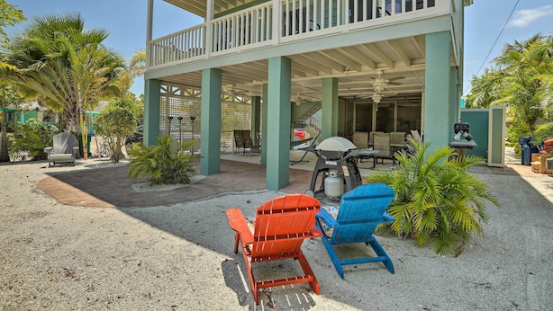 Un espace extérieur abrité comprenant deux fauteuils Adirondack, un barbecue et une terrasse avec des tables et des chaises.