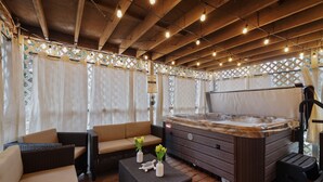A covered outdoor area with a hot tub, wicker furniture, and string lights. - Lakeview|! HotTub| Game Room| Community Pool! (Pocono Summit)
