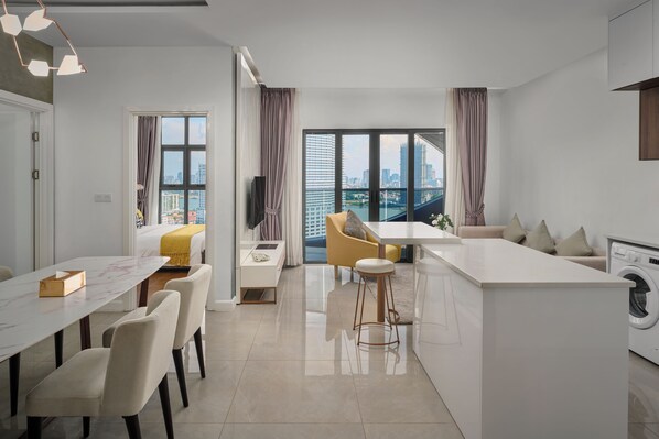 A modern kitchen with a central island, a dining area with a table and chairs, and a large window with a city view.
