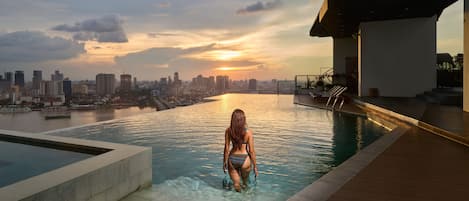 Een buitenzwembad, ligstoelen bij het zwembad