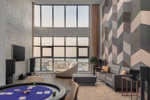 A modern living room with a pool table, comfortable seating, and large windows offering a city view.