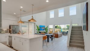 A spacious kitchen with a central island, pendant lighting, and a dining area with a view of the outdoors.