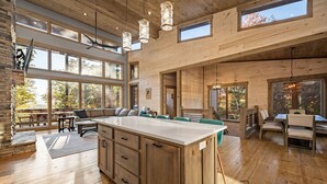 A spacious kitchen with a large island, wooden cabinetry, and ample natural light from large windows.
