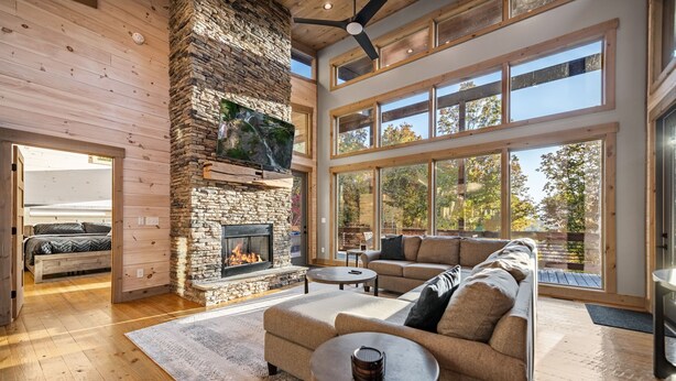 A spacious living room with a stone fireplace, large windows, and a cozy seating area.