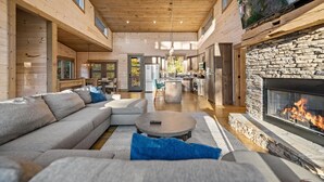 A modern log cabin interior with a living room, kitchen, and fireplace.