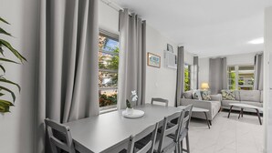 Ein modernes Wohnzimmer mit Essbereich, ausgestattet mit einer Sofagarnitur, einem Esstisch und einer Topfpflanze.