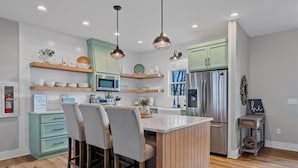 Una cocina moderna con una isla central, taburetes de bar y un refrigerador.