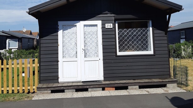 A small, single-story building with a dark exterior and white-framed windows, featuring a number '316' on the door. - 5 minutes from the beach, campsite, very quiet (Le Coq)
