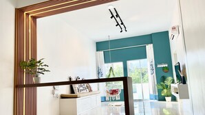 Un hall d’hôtel moderne au design épuré et minimaliste, avec une palette de couleurs composée de blanc et de turquoise, un espace salon central agrémenté d’un banc et un grand miroir qui reflète la pièce.