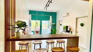 Une cuisine moderne avec un bar en bois et des tabourets, une grande fenêtre et un mur d’accent de couleur turquoise.