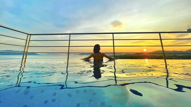 Une personne dans une piscine, avec une vue sur le coucher de soleil.