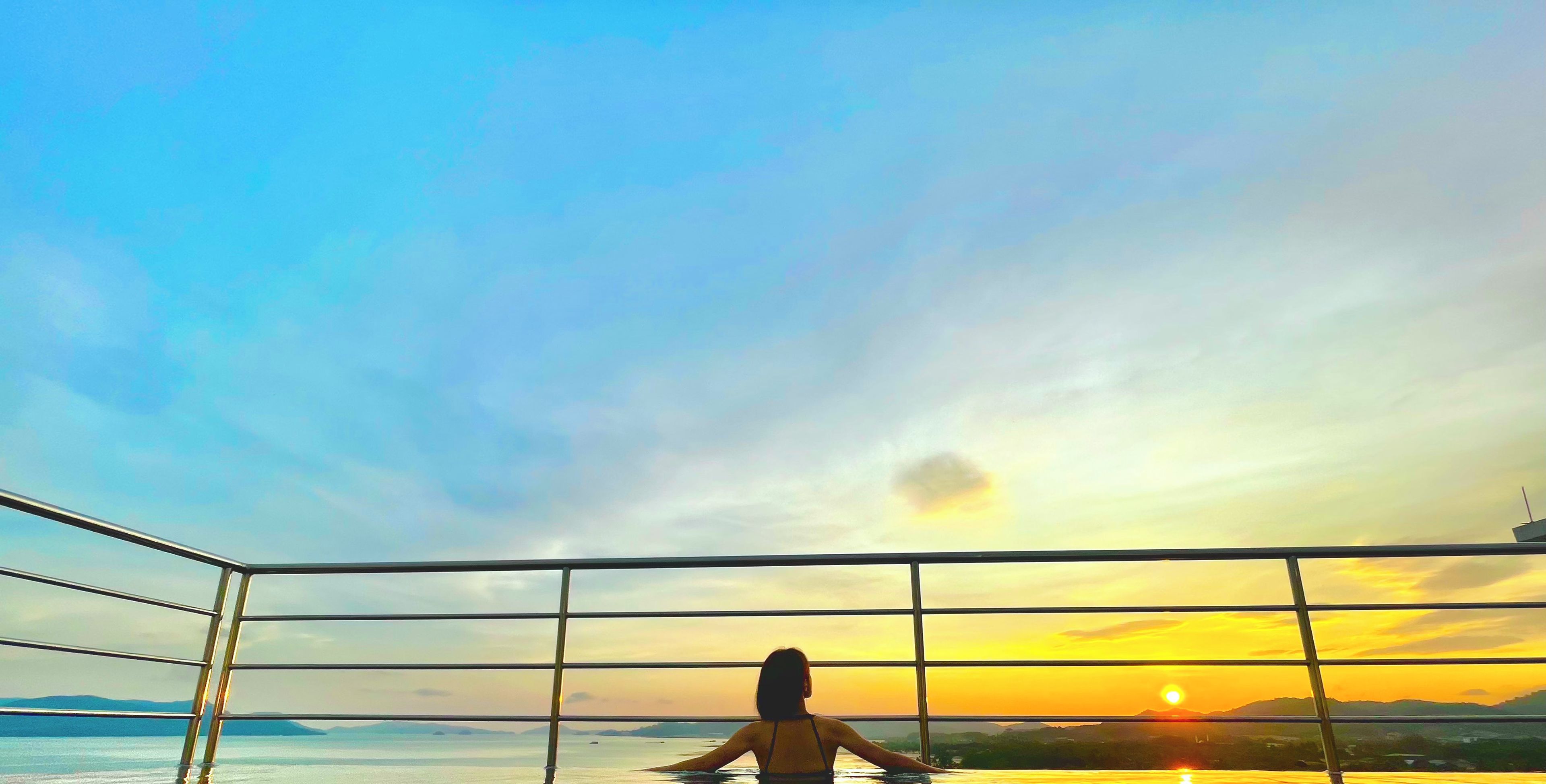 A person in a swimming pool with a sunset view.