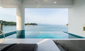 A infinity pool with a clear view of the sea and distant land. - Blue Mango Pool Villa & Resort (Yeosu)