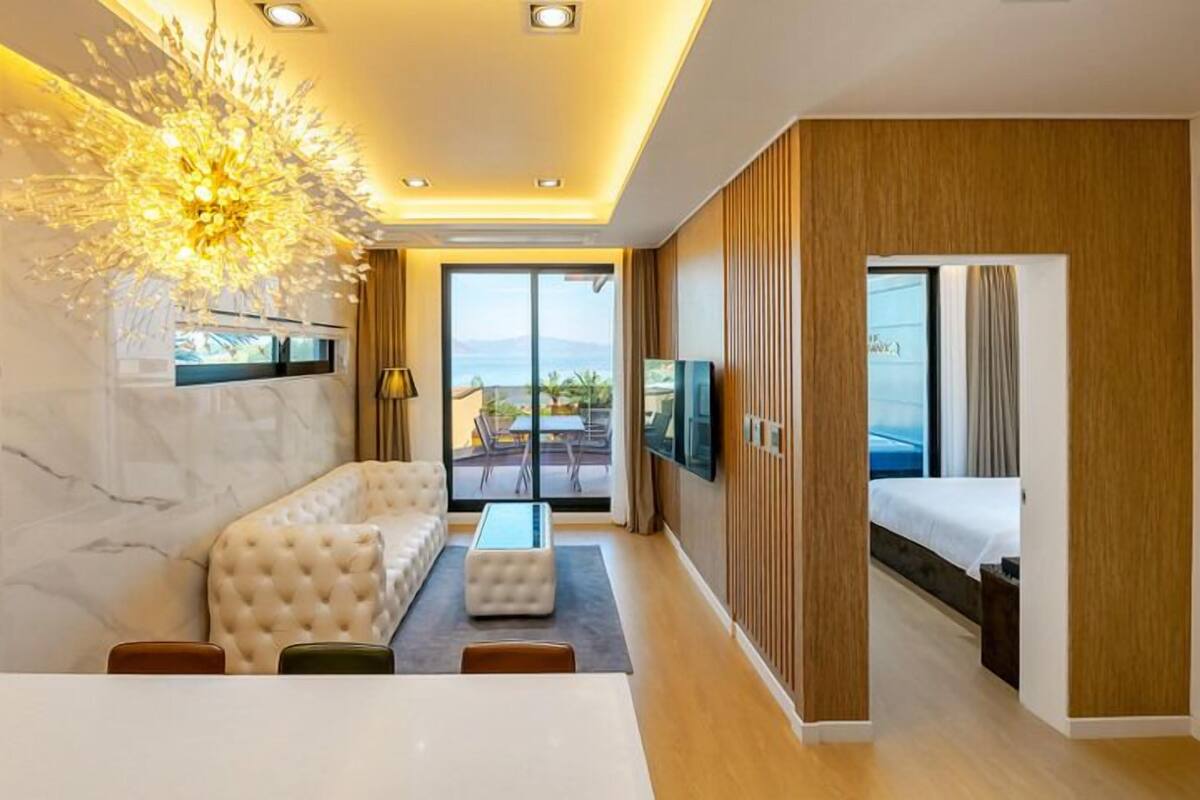 Une chambre d’hôtel moderne équipée d’un canapé, d’une table à manger, d’une télévision et d’un balcon avec vue.