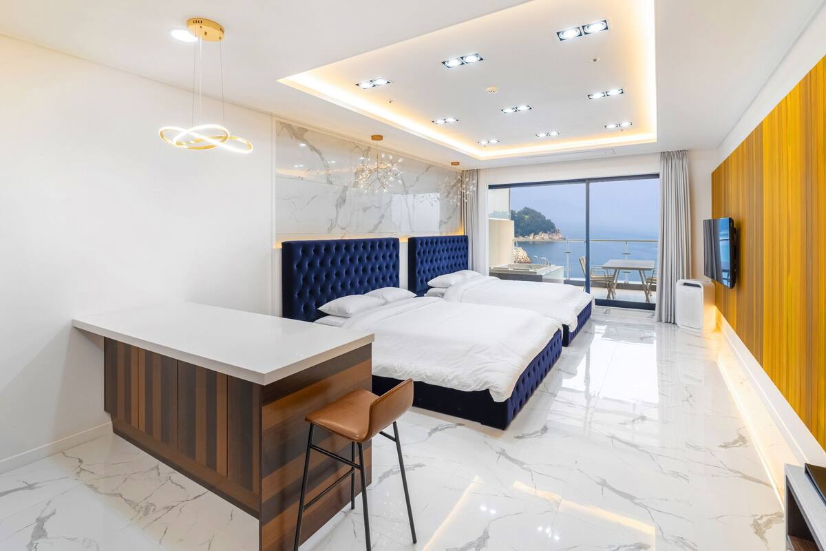 Une chambre d’hôtel moderne avec un grand lit, un bureau et une vue sur la mer.