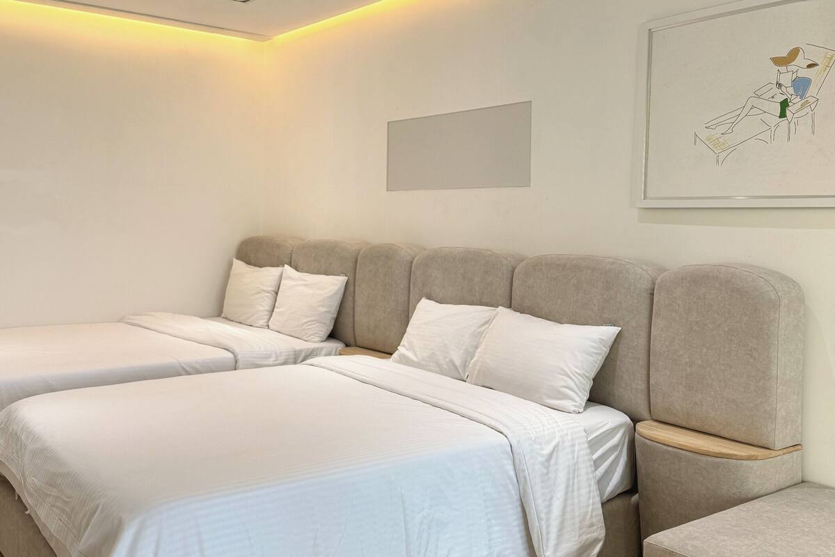 Une chambre d’hôtel avec deux lits, une tête de lit, une table de chevet et une œuvre d’art encadrée au mur.