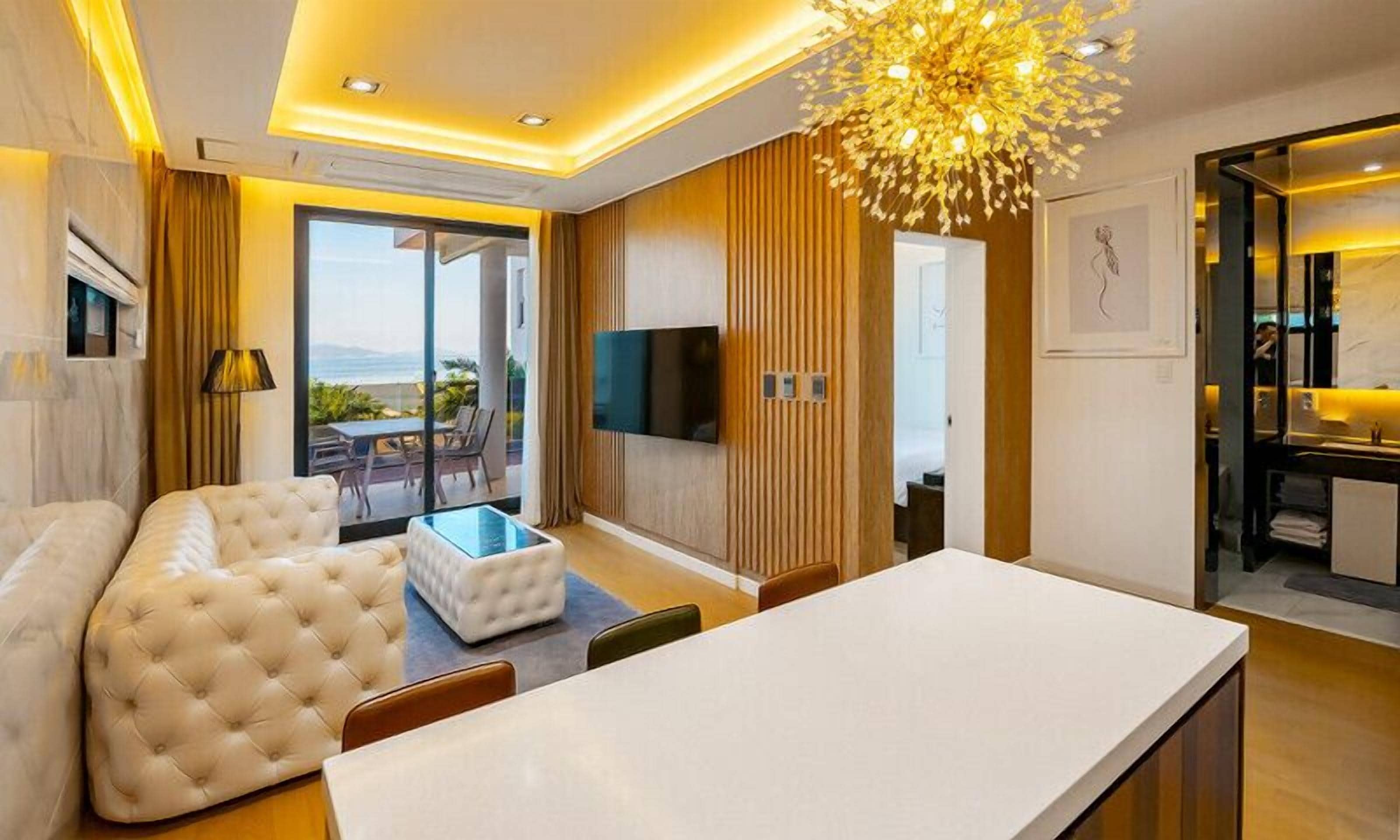 A modern living room with a large sofa, a glass coffee table, and a dining area with a white table.