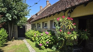 Un bâtiment traditionnel avec un toit en tuiles, des murs en pierre et un chemin pavé.