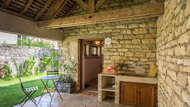 Une pièce aux murs de pierre, avec un plafond en bois, une petite table et des chaises.