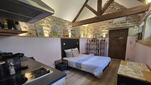Une petite chambre comprenant un lit, un petit bureau et une kitchenette.