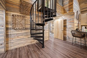 A spiral staircase with a wooden interior, a dining area with a table and chairs, and a kitchen area with cabinets and appliances.