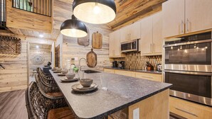 A modern kitchen with a central island, stainless steel appliances, and wooden cabinetry.