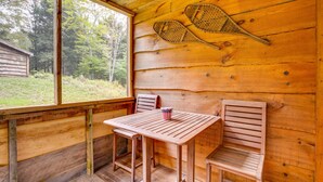 A wooden cabin with a table and two chairs, a tennis racket, and a small American flag decoration.