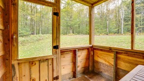 A wooden cabin with large windows offering a view of a forested area.