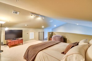 Ein Schlafzimmer mit einem großen Bett, einem Fernseher auf einer Kommode und einer Treppe, die in ein Obergeschoss führt.