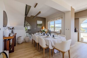 Comedor con una mesa dispuesta para seis personas, una escalera y vistas al exterior.
