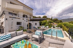 Zona junto a la piscina con un edificio blanco, mobiliario exterior y una alberca.