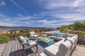 A deck with outdoor furniture, a table with drinks, and a scenic view of the landscape. - Luxury and Modern villa with magnificent sea view & Gulf of Saint Tropez (Cavalaire-sur-Mer)