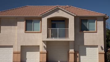 A two-story house with a numbered address, a balcony with a railing, and two garage doors.