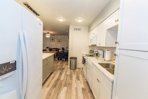 A modern kitchen with white cabinets, stainless steel appliances, and a herringbone-patterned backsplash.